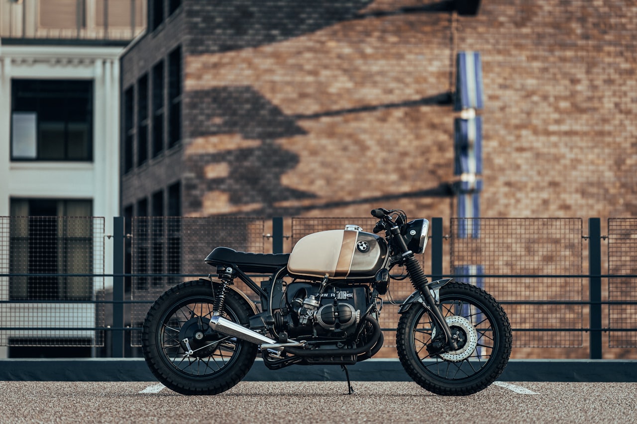 A red retro-styled naked motorcycle with an exposed steel frame and round headlight parked on a city street