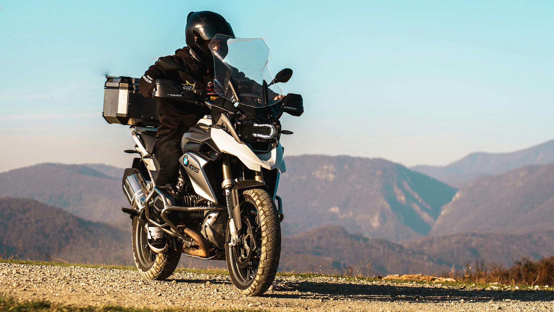 Rider on a BMW adventure motorcycle on a bright mountain ridge